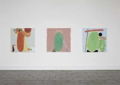 Three colourful pastel toned abstract paintings on a white wall