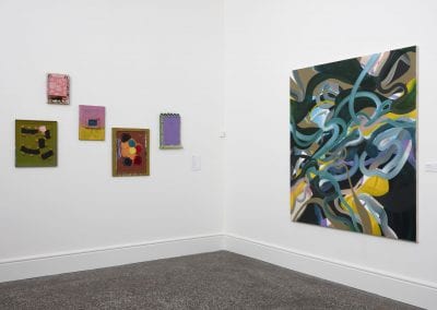 Gallery interior with various colourful abstract paintings of different sizes on the wall