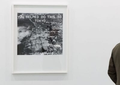 Framed photo-text artwork showing aerial view of land; reads 'You helped do this to Tokyo'