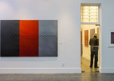 Gallery interior with large abstract painting on wall, in grey and red blocks