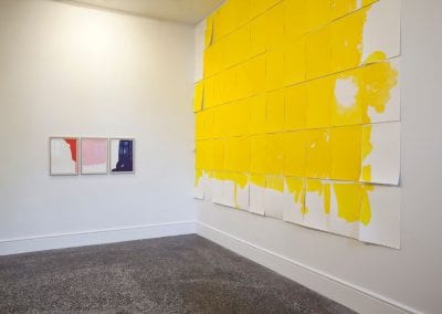 Large yellow painting installation, with smaller abstract paintings on facing wall