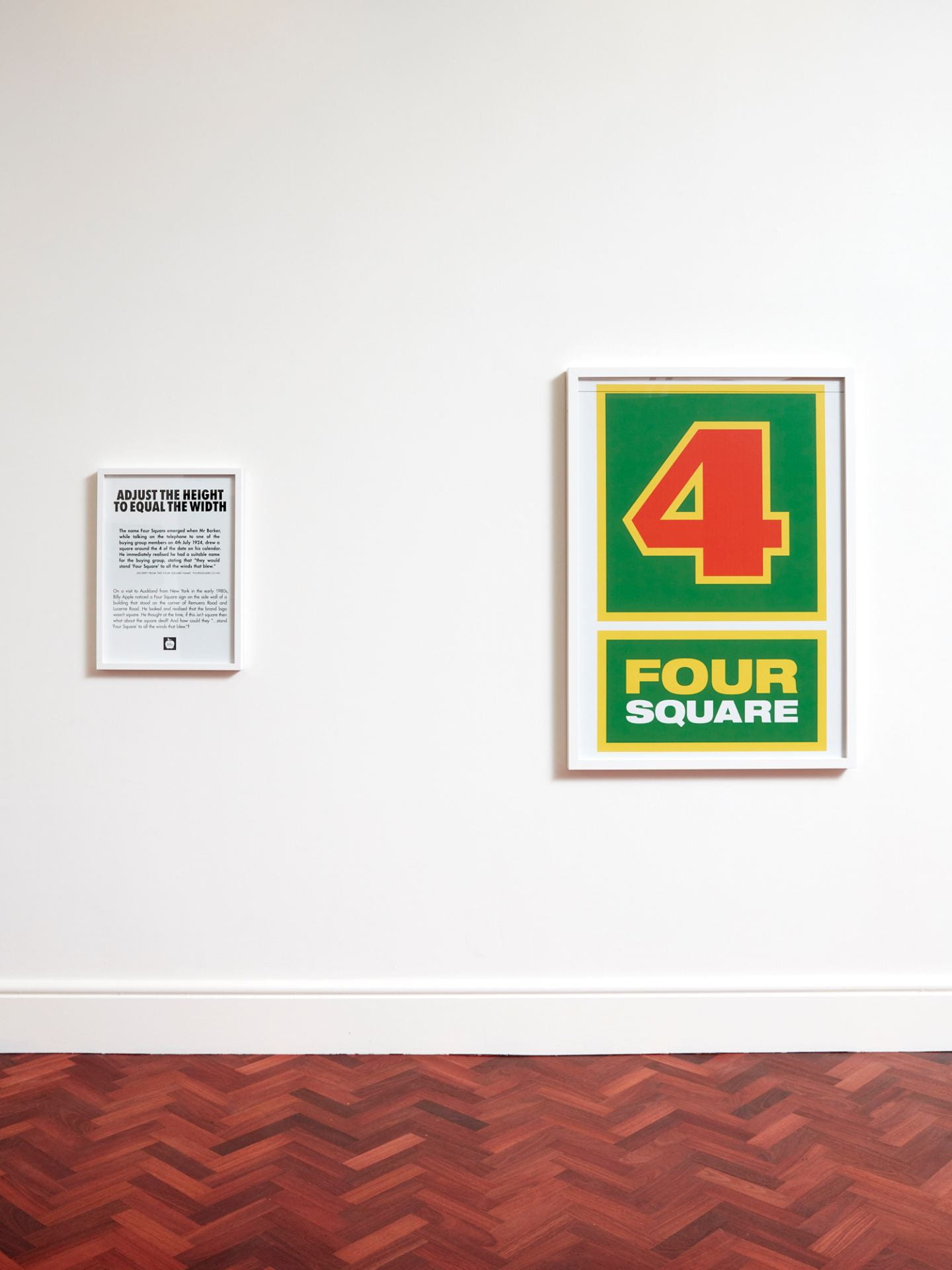 Two framed works mounted on a gallery wall. The left artwork contains black text on a white background, not legible from this distance, but which explains that the Four Square logo is not actually a perfect square. The right artwork is a replica of the Four Square logo, a red '4' surrounding by green with 'Four Square' written in yellow underneath.