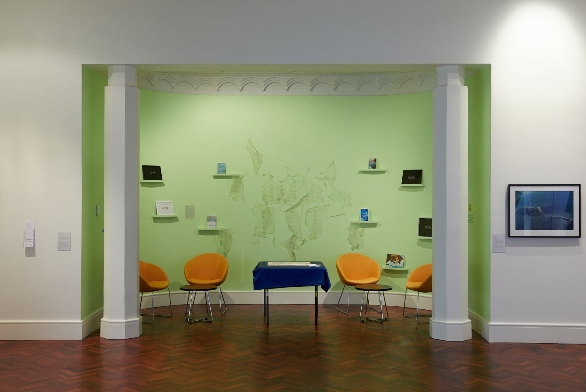 In the centre of an alcove space, pieces of very thin translucent cellulose are pasted to a green wall. The cellulose has text printed on it.