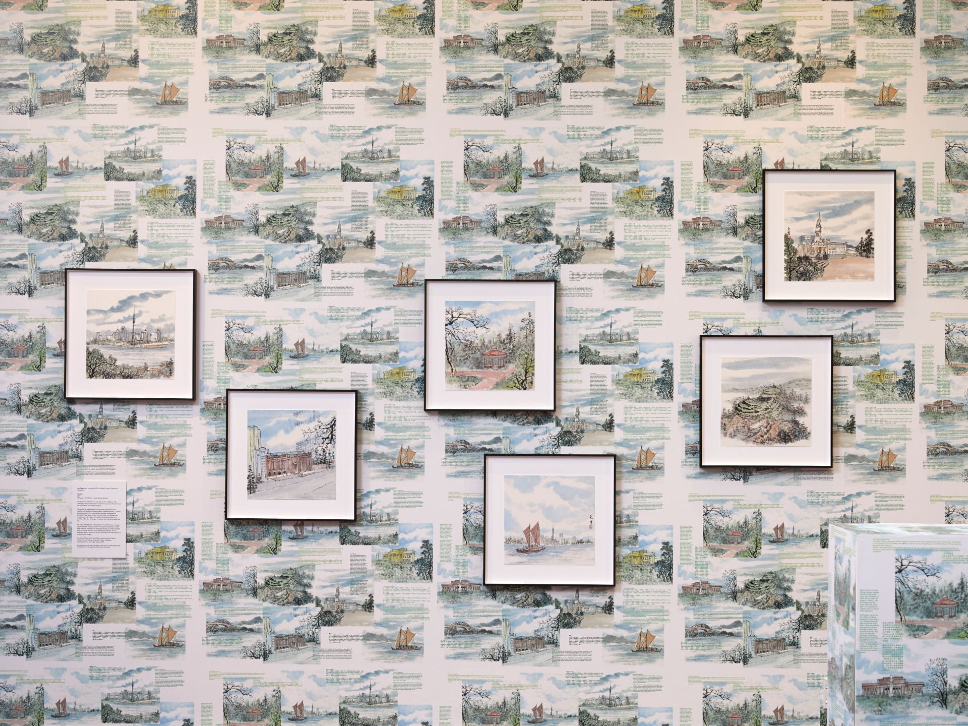 Six watercolours of Auckland landmarks hang on a wall, which has been wallpapered with repeating copies of those same prints.