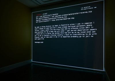 A command terminal window open displaying detainees messages, projected as a film onto a wall.