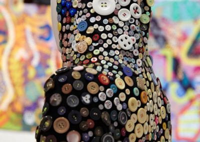 A close-up of the back of a mannequin wearing a onesie covered in buttons of all different shapes, colours and sizes.