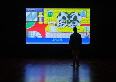 A film projected in a dark room. The film shows a bright animation of a cartoon cow sitting in an opulent golden room. The subtitle along the bottom of the film reads "once upon a time".