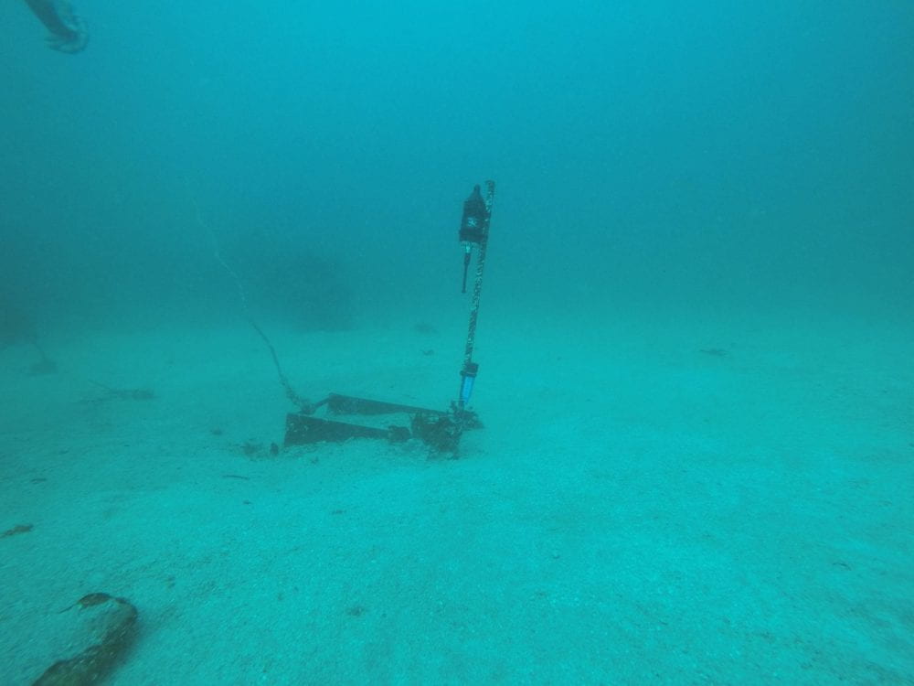 A hydrophone submerged into the ocean floor, in the middle of a deep blue ocean.