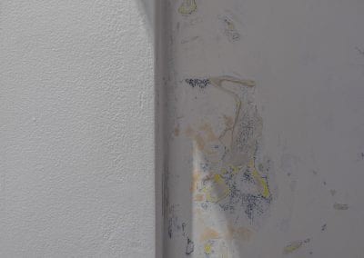 Close-up of the interior Booth walls, which have been sanded down to reveal layers of yellow paint in patches underneath.