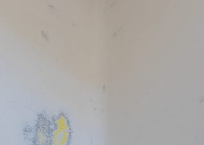 Close-up of the interior Booth walls, which have been sanded down to reveal layers of yellow paint in patches underneath.