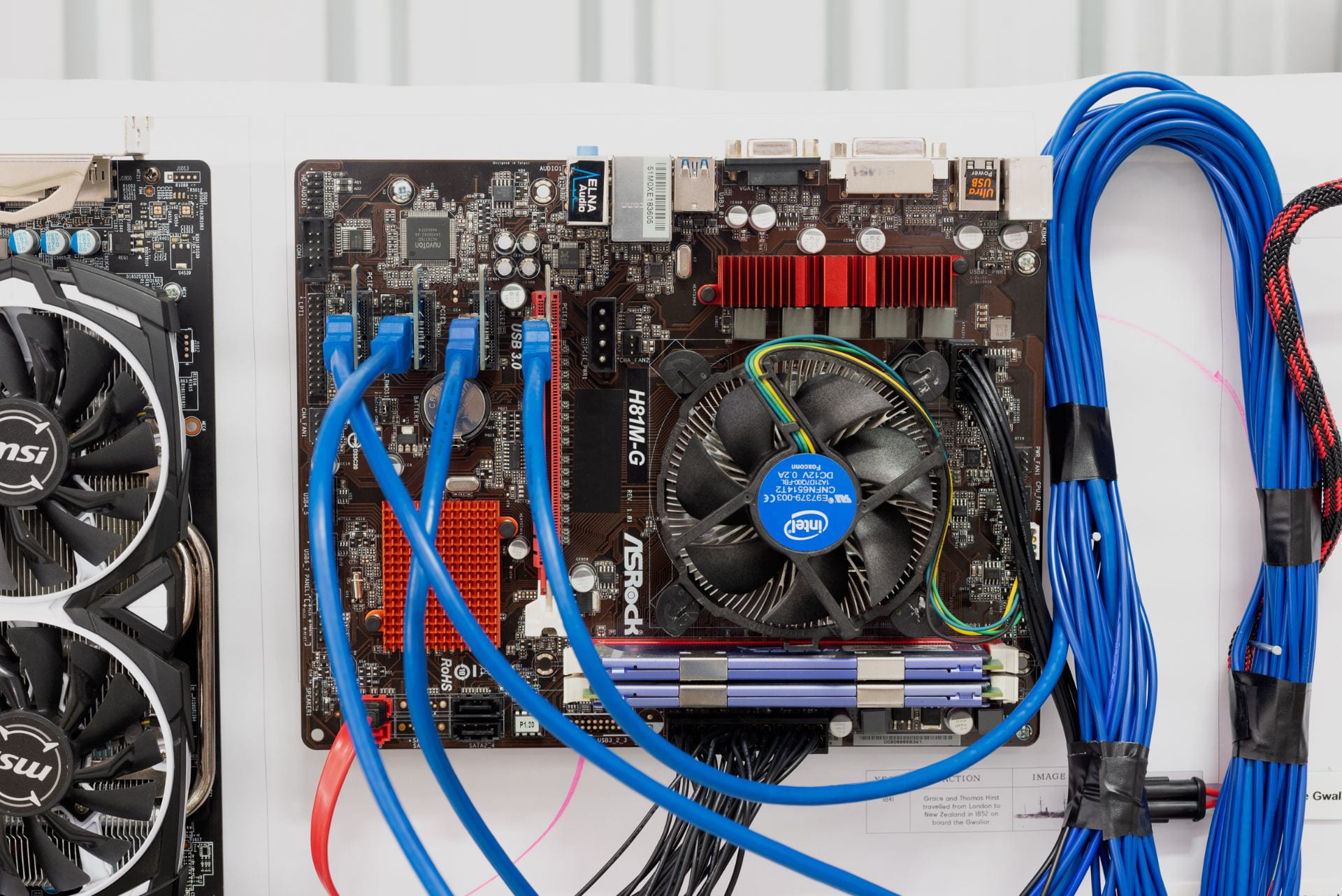 A series of blue cables mounted onto a board, hooked up to a CPU with a fan on it.