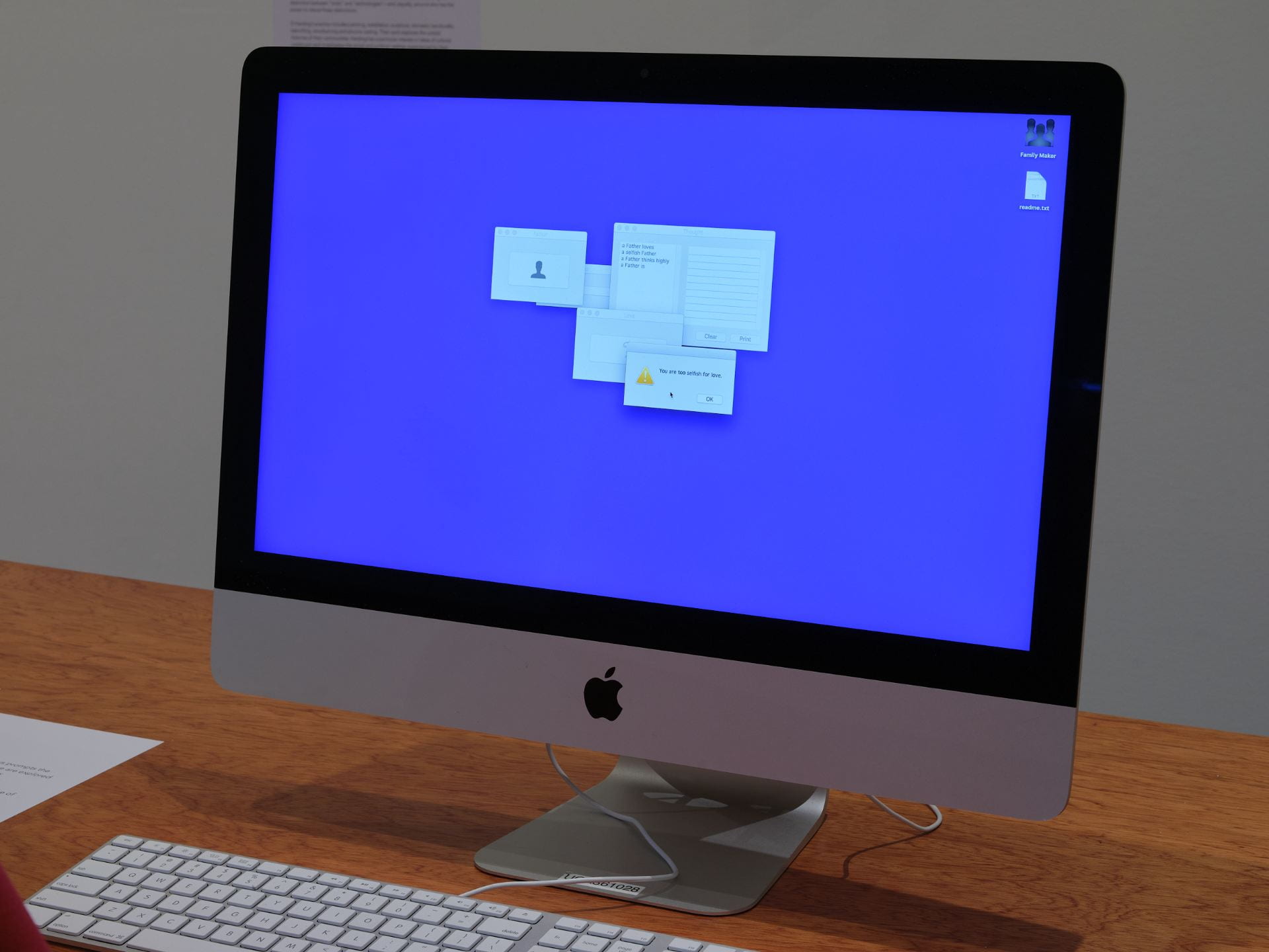 A Mac computer sits on a table. On the computer, a software application is open against a bright purple background. The application has lots of little windows clustered in the centre of the desktop.