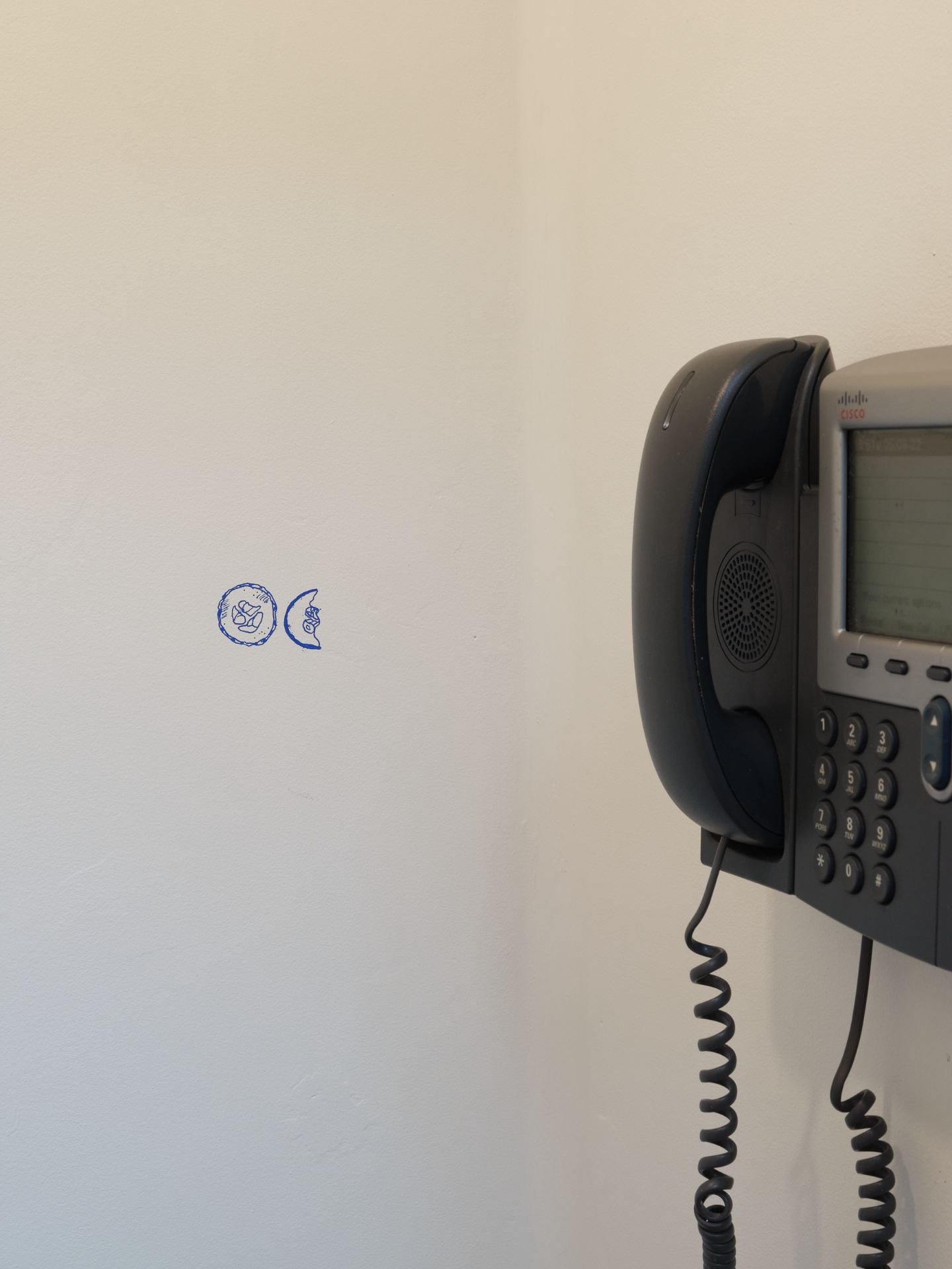 A wall mounted phone in the phone booth. To its right is a little sketch of cucumber slices.