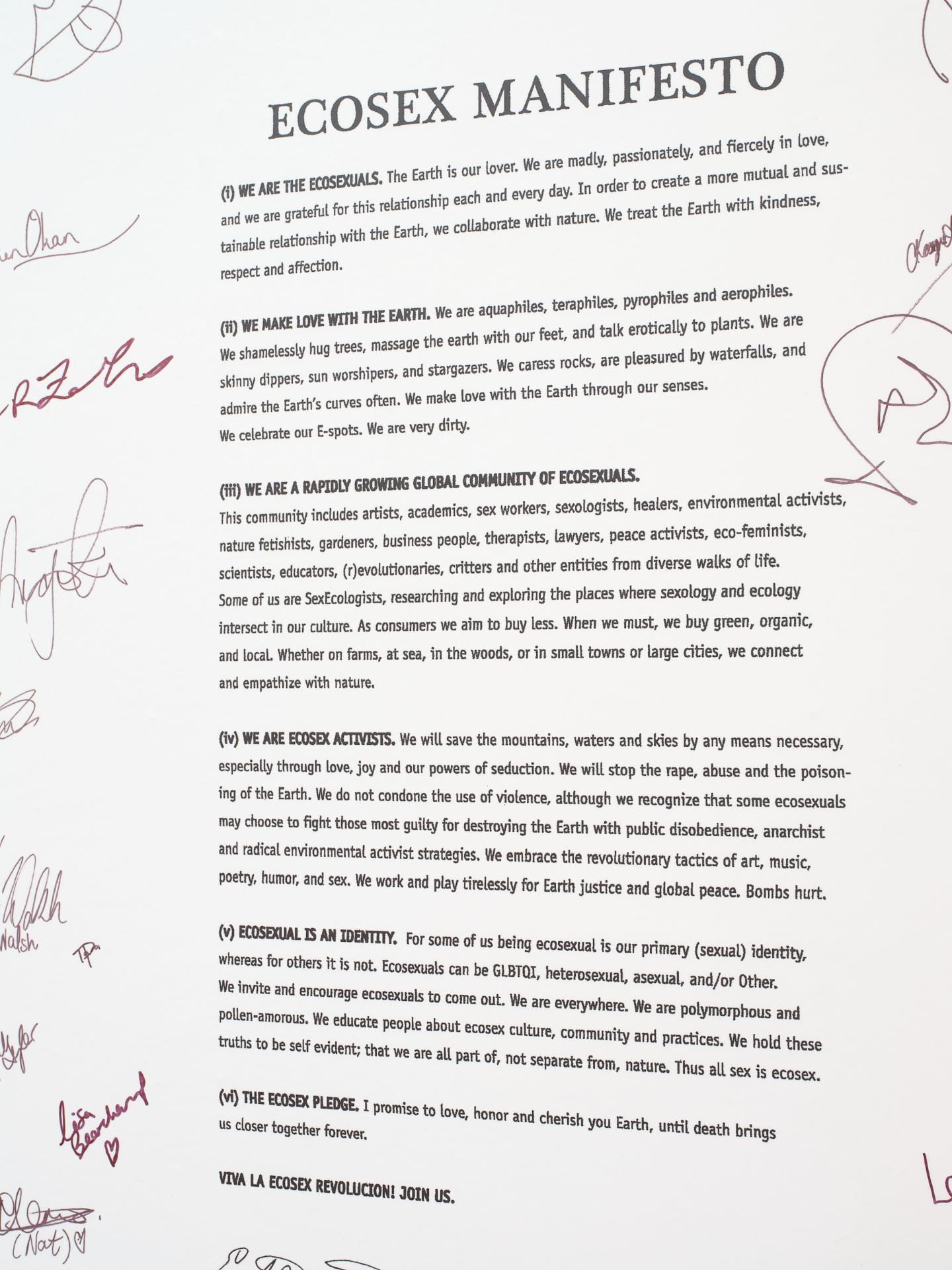 A piece of printed text on a wall, titled 'Ecosex Manifesto'. There are multiple signatures around the manifesto.
